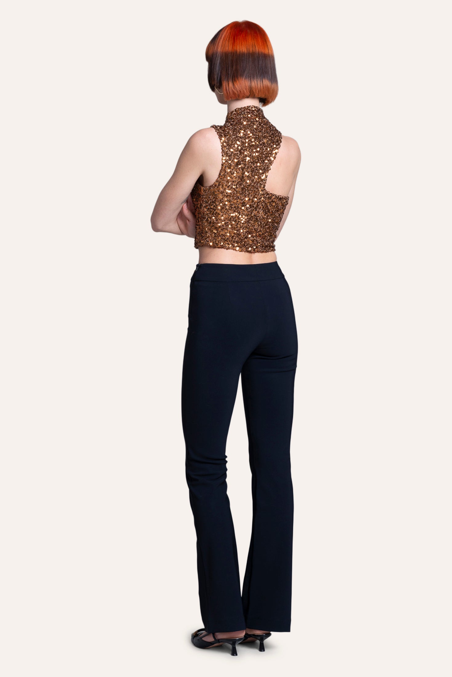 Person wearing a sequined top and black pants on a white background
