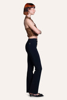 Woman wearing a gold sequin top and black pants on a white background
