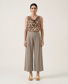 Woman wearing a leopard print top and beige wide-leg pants on a white background