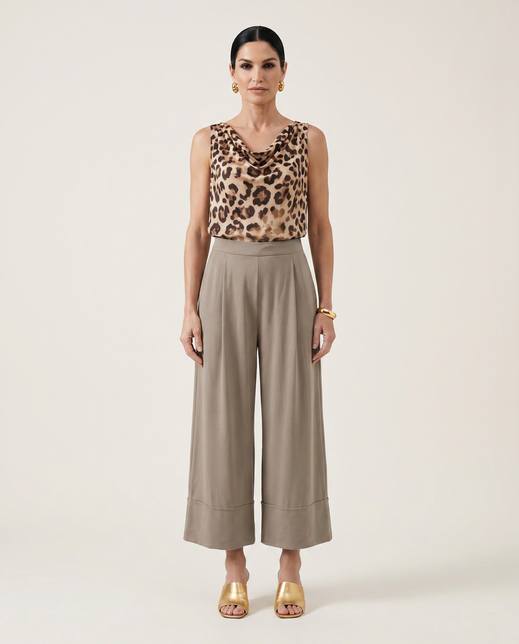 Woman wearing a leopard print top and beige wide-leg pants on a white background