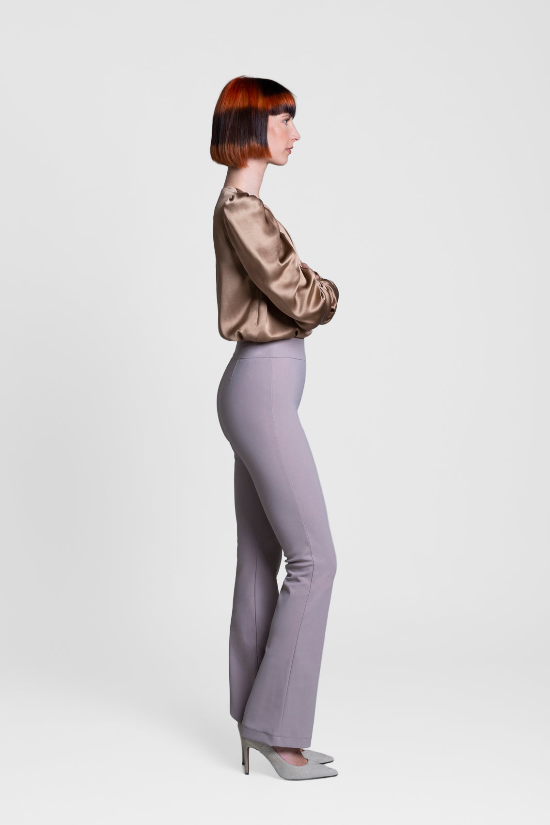 Model wearing a gold blouse and beige pants on a white background